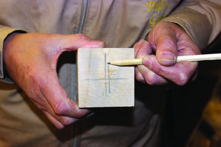 Person marking wood with pencil for cutting.