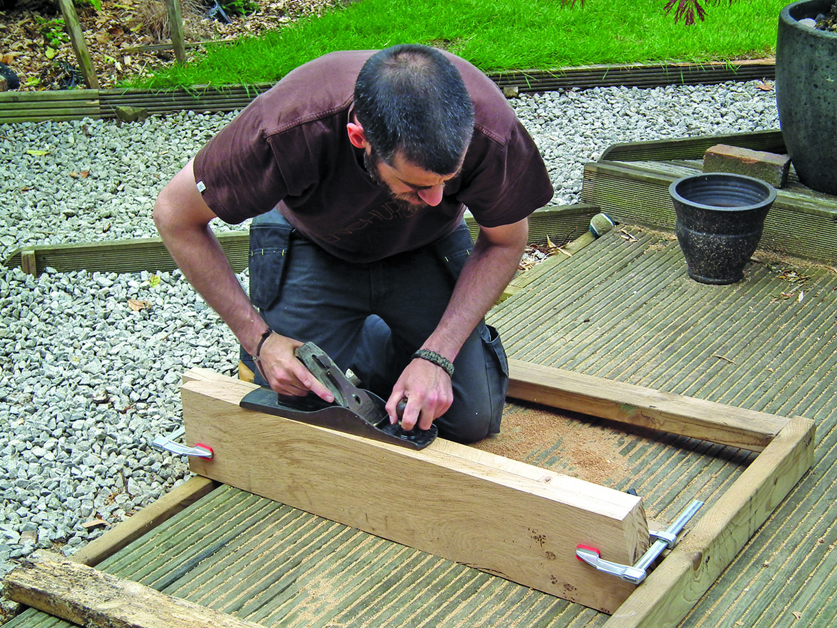 Lee Stoffer using a hand plane to clean up the pair of boards used for the pivot bed.