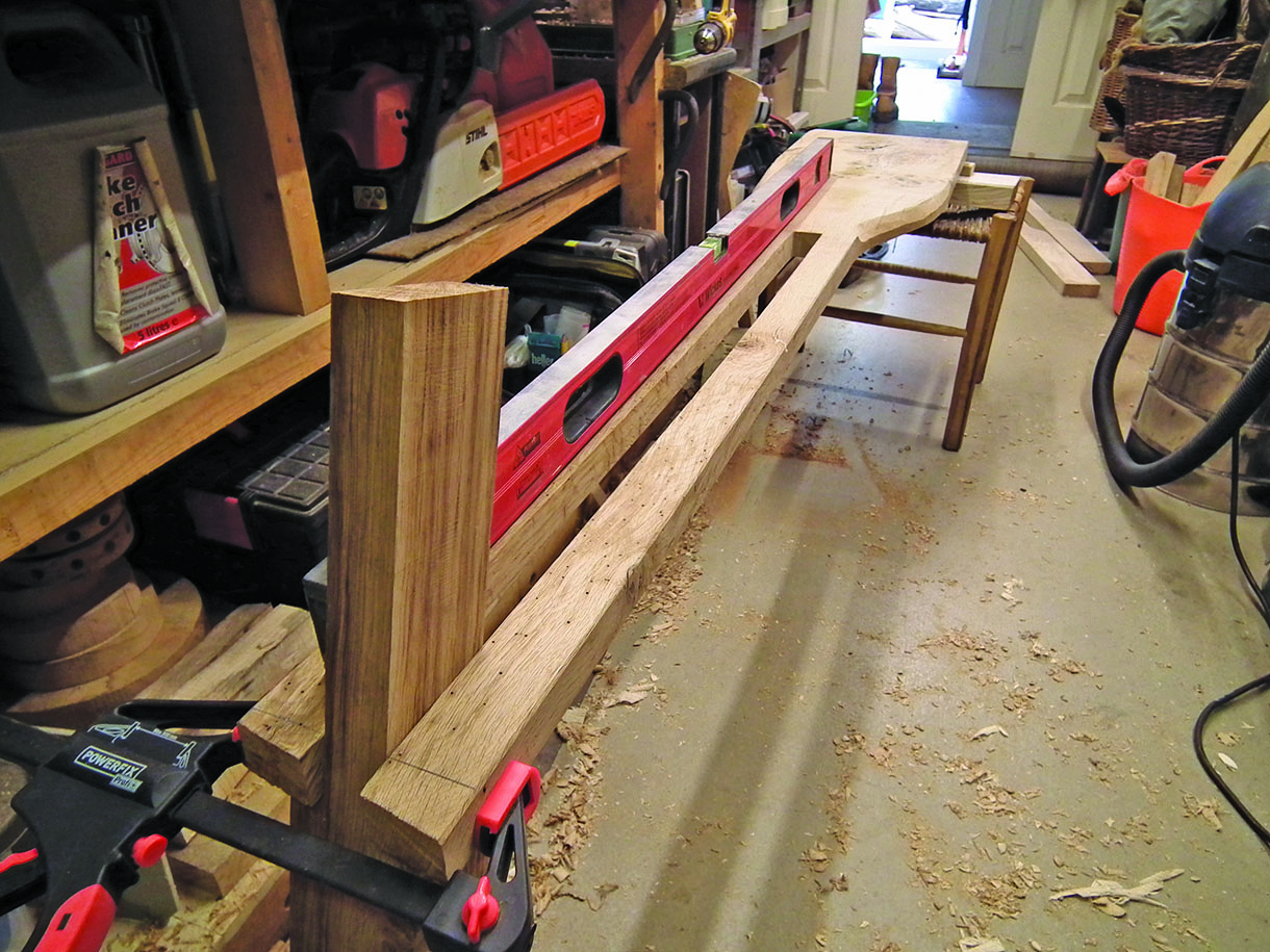 Clamping and assembling the leg on the seat board. A level is being used to test the angle.