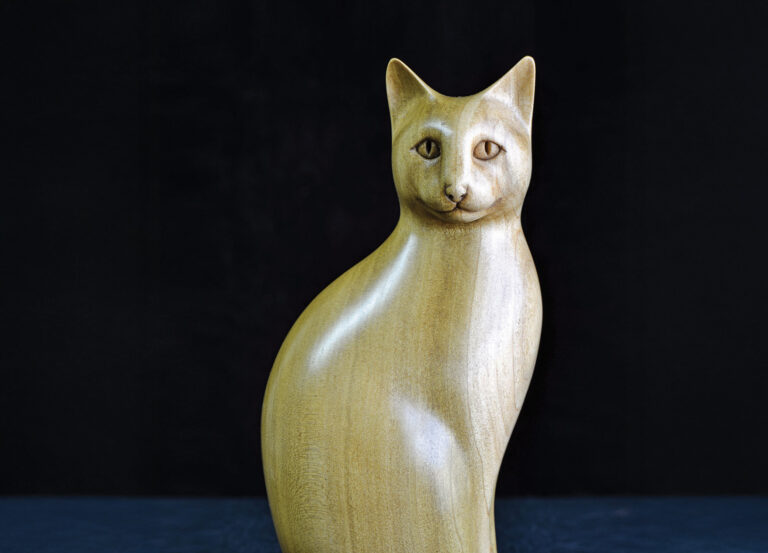 Wooden cat sculpture against dark background