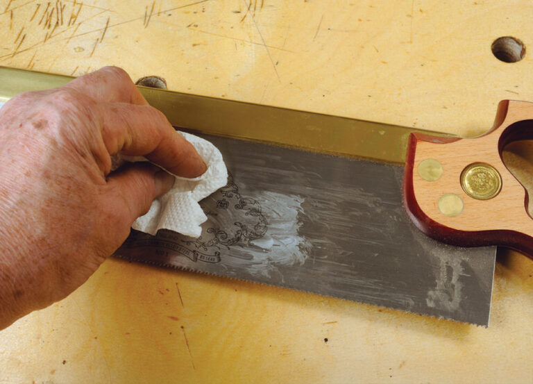 Person cleaning saw blade with cloth