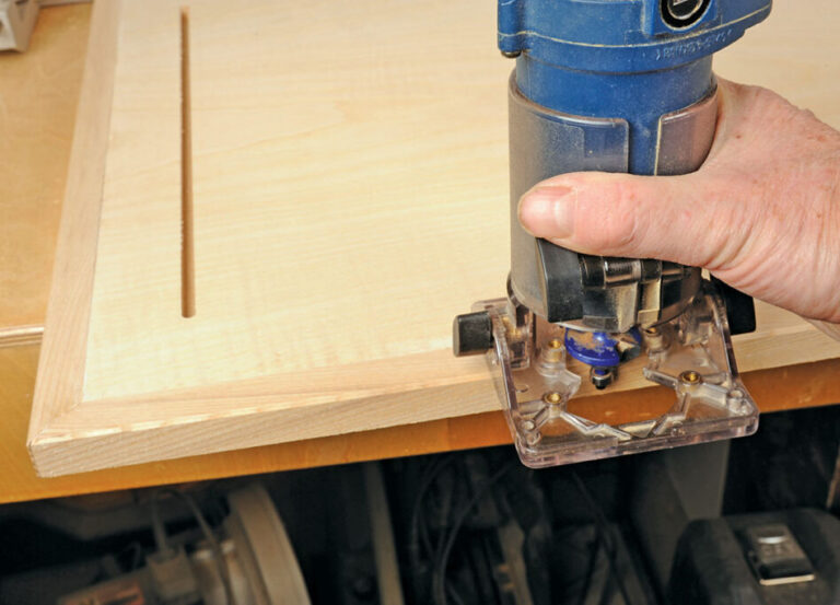Person using router on wooden board edge.