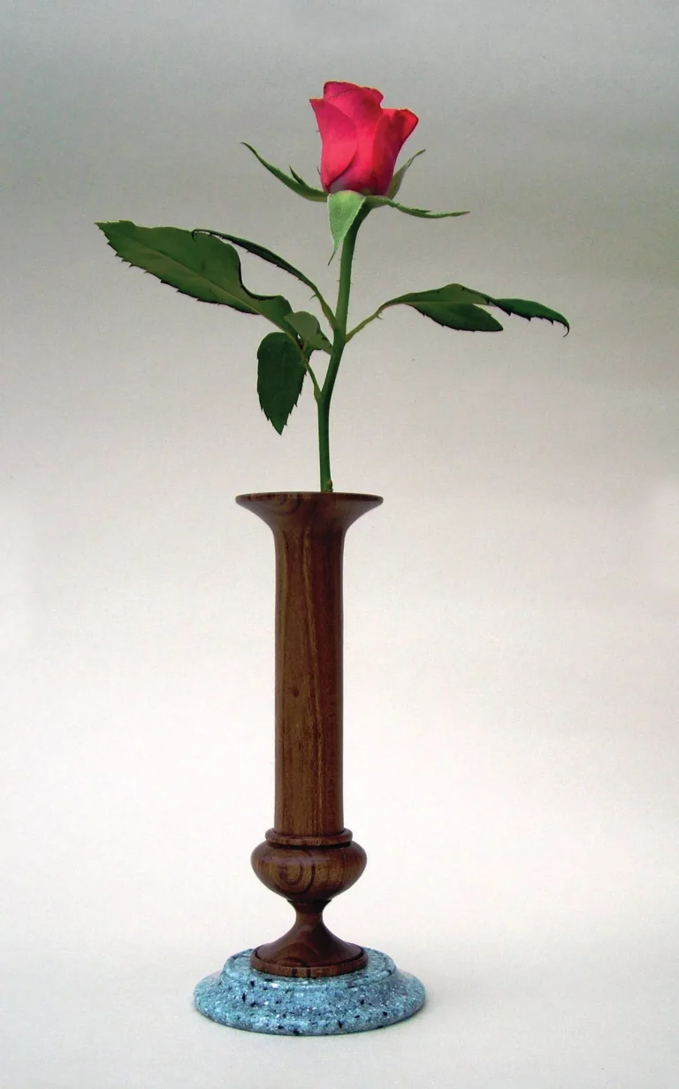 Single red rose in a tall brown vase.