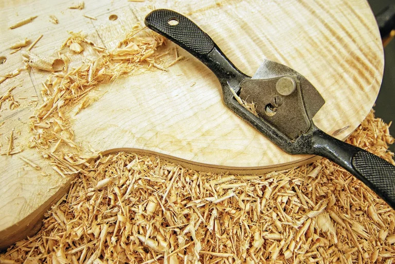 Wood carving with hand tool and wood shavings.