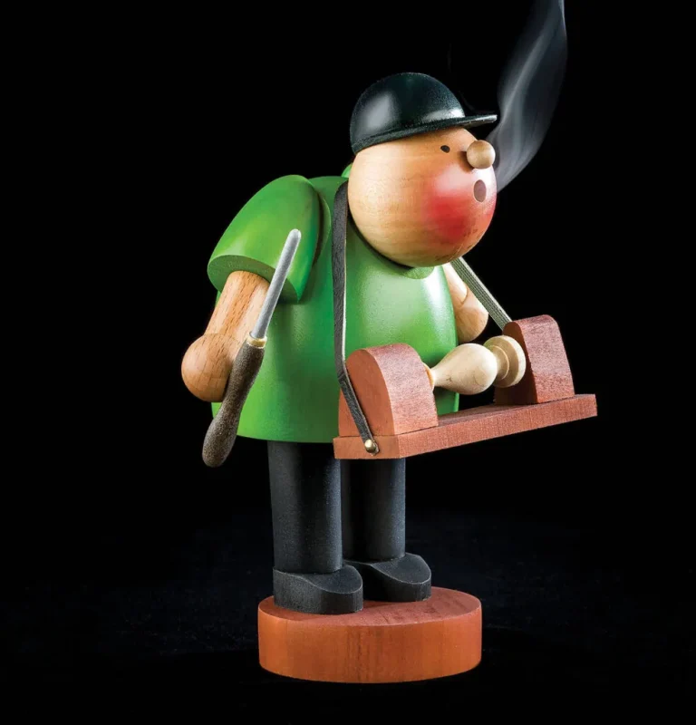 Wooden smoker figurine with green shirt and black hat.