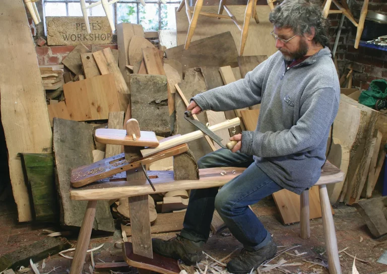 Man woodworking in cluttered workshop.