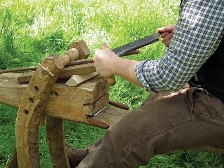 Man using shave horse for woodworking in nature.