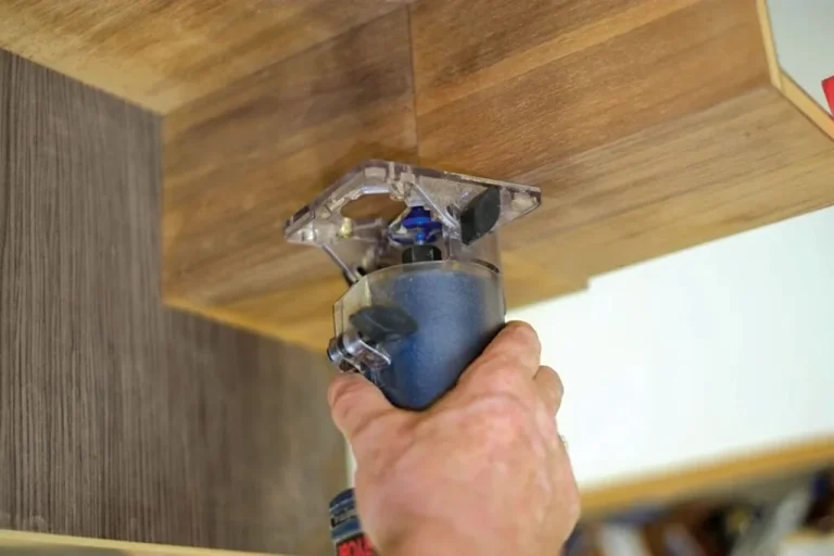 Hand holding a router for wood trimming work.