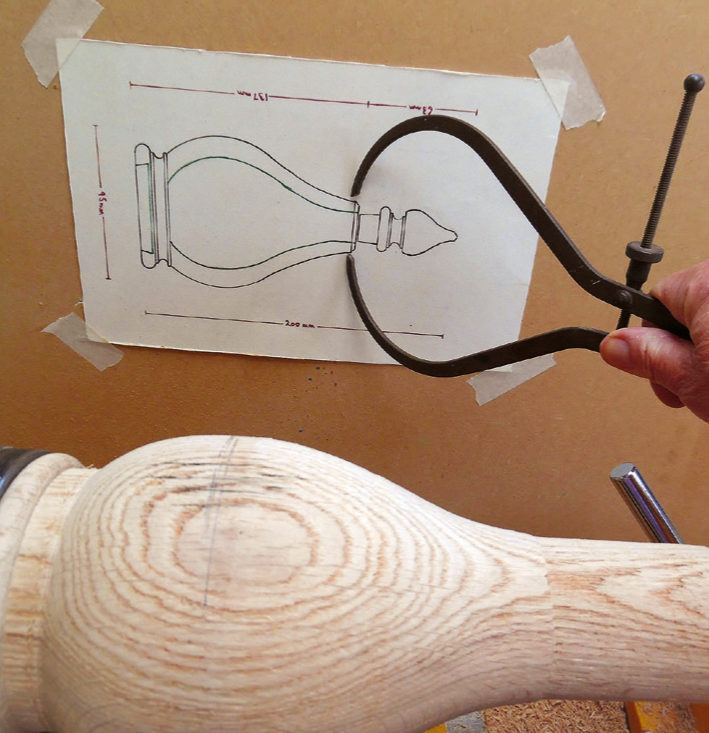 Woodturning project measured against design sketch with calipers.