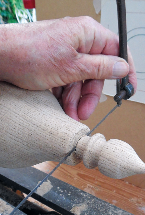 Woodworker using a coping saw on a detailed project.