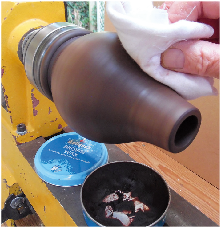 Polishing wood on a lathe with brown wax.