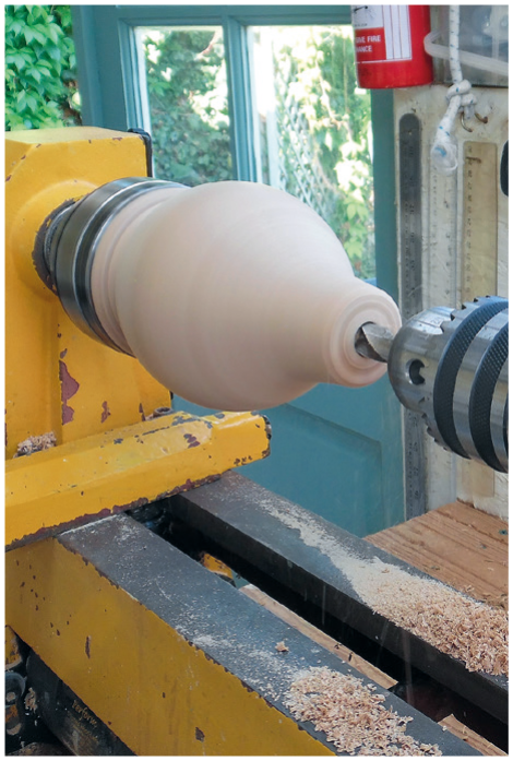 Wood lathe shaping a piece of wood.