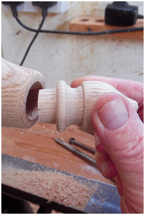 Inserting wooden dowel into hole on lathe.