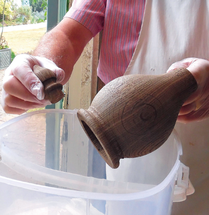 Person examining wooden vase and lid.