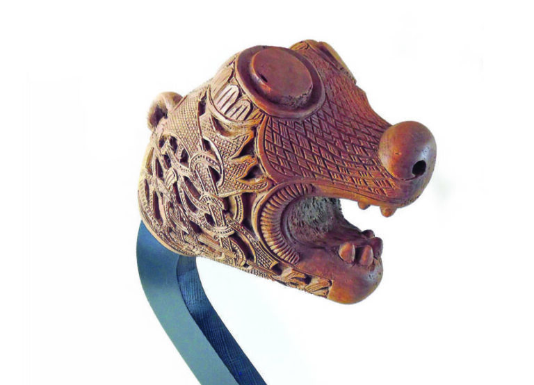 Carved wooden animal head sculpture with intricate patterns.