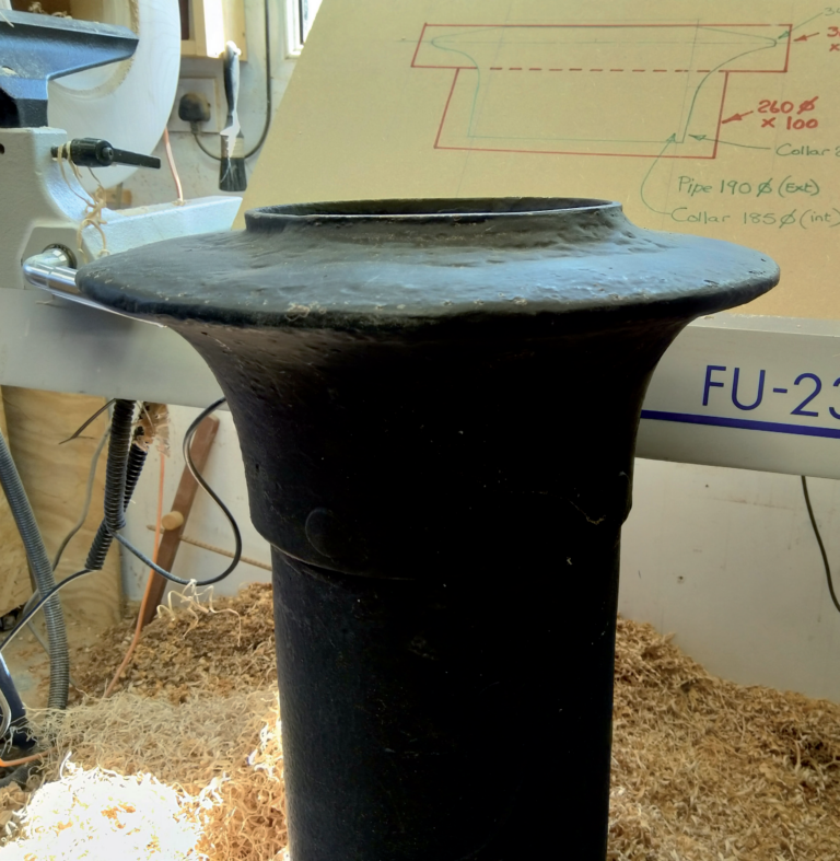 Close-up of black pipe with technical drawing behind.