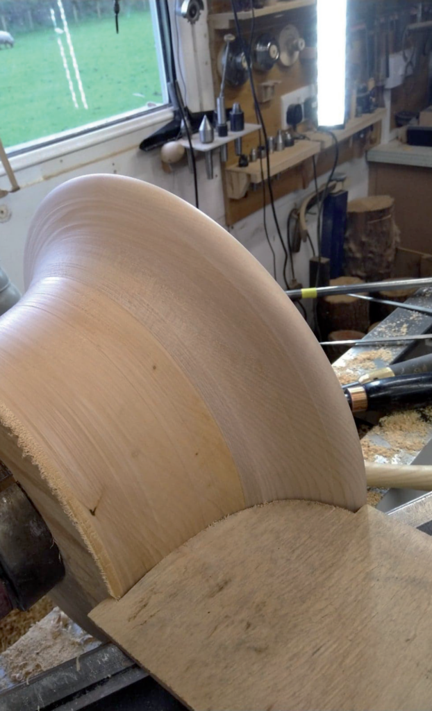 Wood being turned on a lathe in workshop.