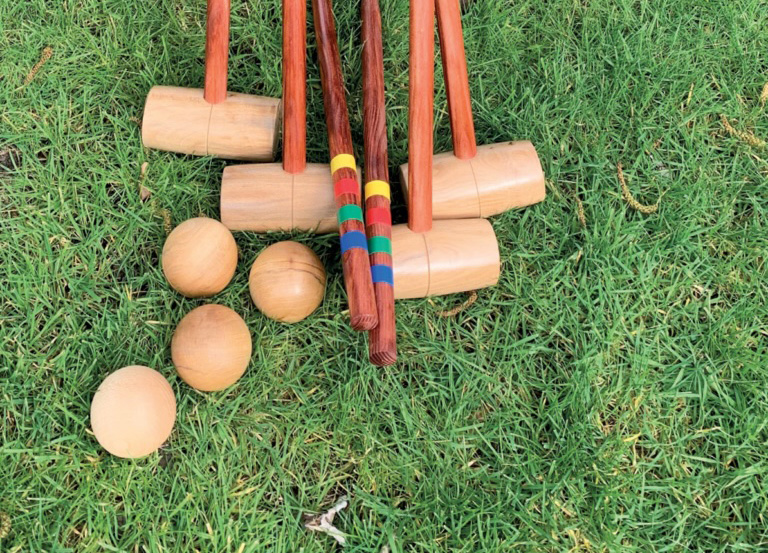 Croquet mallets and balls on grass lawn.