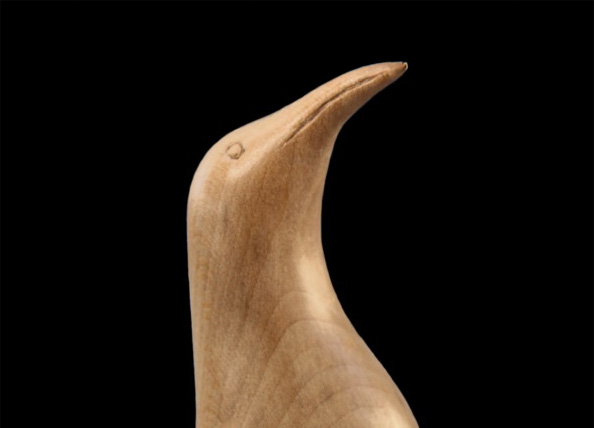 Wooden penguin sculpture on black background.