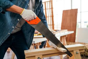 Person sawing wood on workbench.