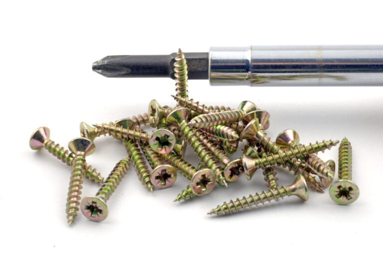 Screwdriver next to pile of screws on white background.