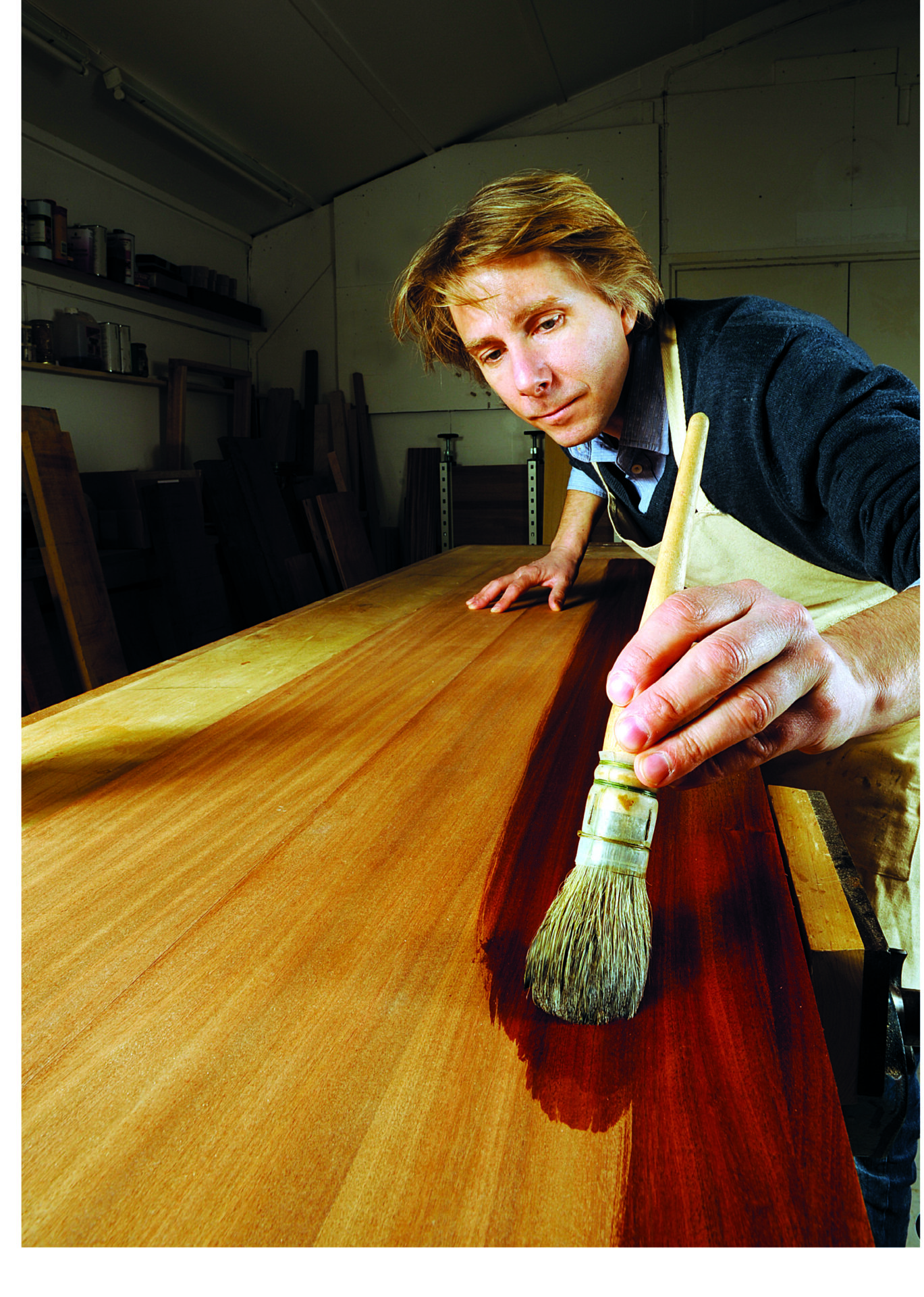 Craftsman varnishing wood in workshop