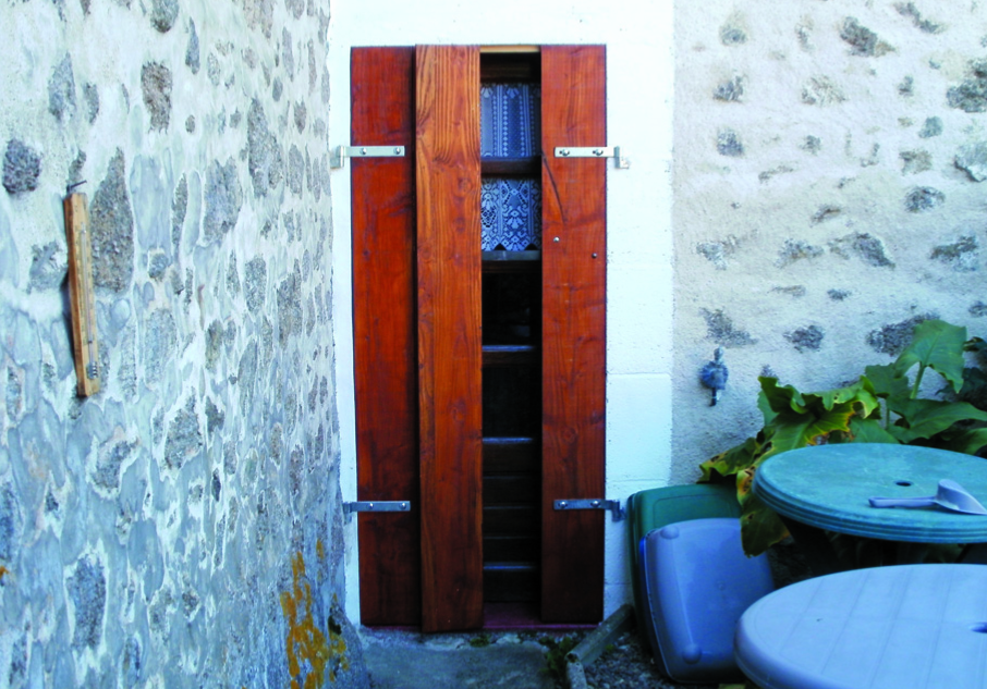 Narrow wooden door between stone walls, outdoor setting.