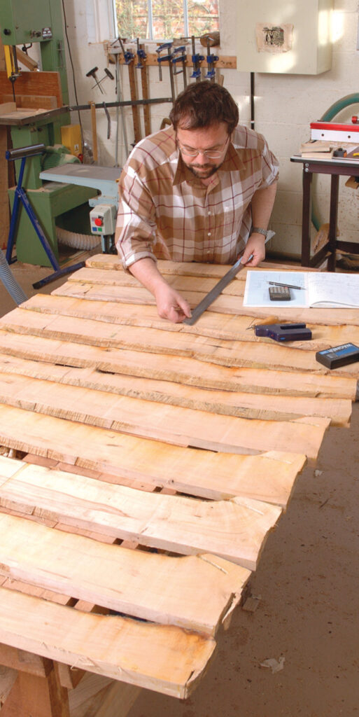 Man measuring wooden planks in a workshop.