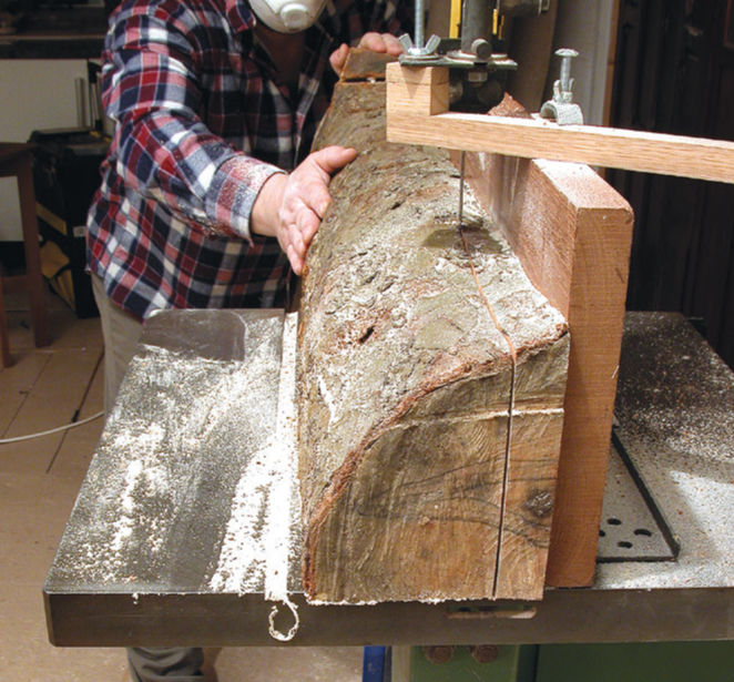 Person cutting wood with bandsaw.