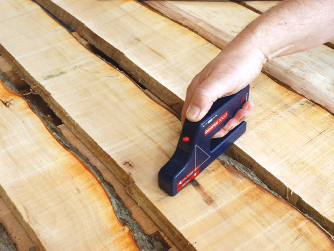 Hand using tool to measure wood thickness.