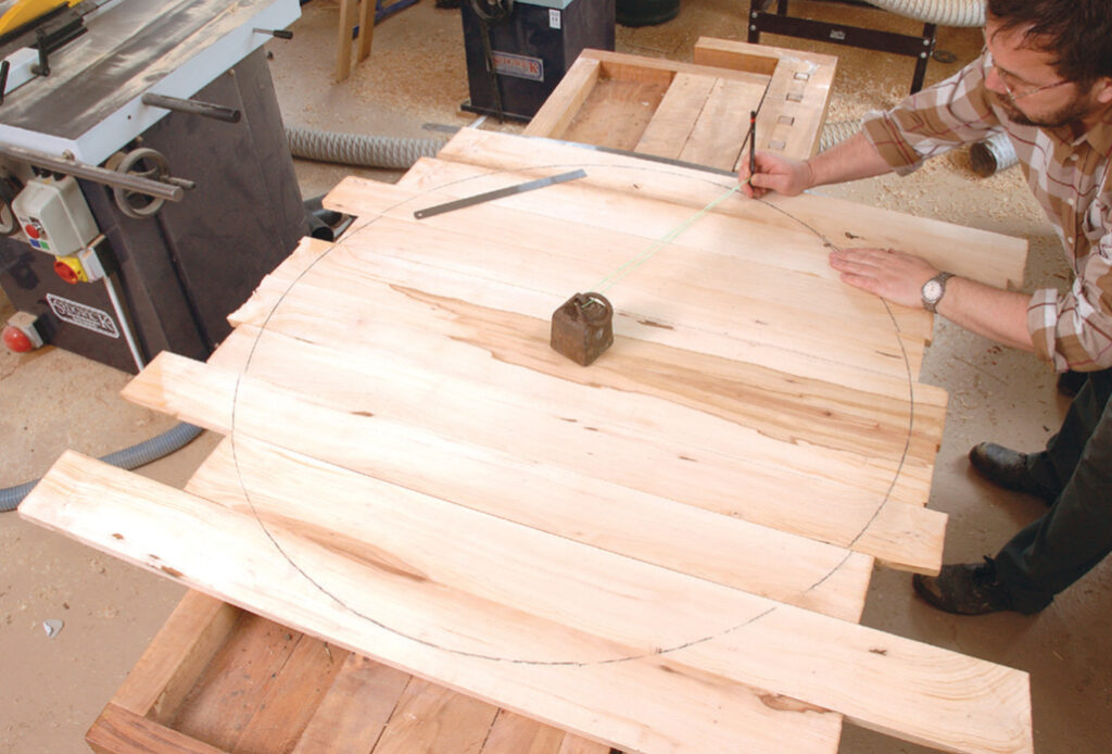 Man drawing circle on wooden board for table.