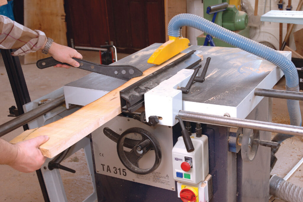 Person using large wood planer in workshop.