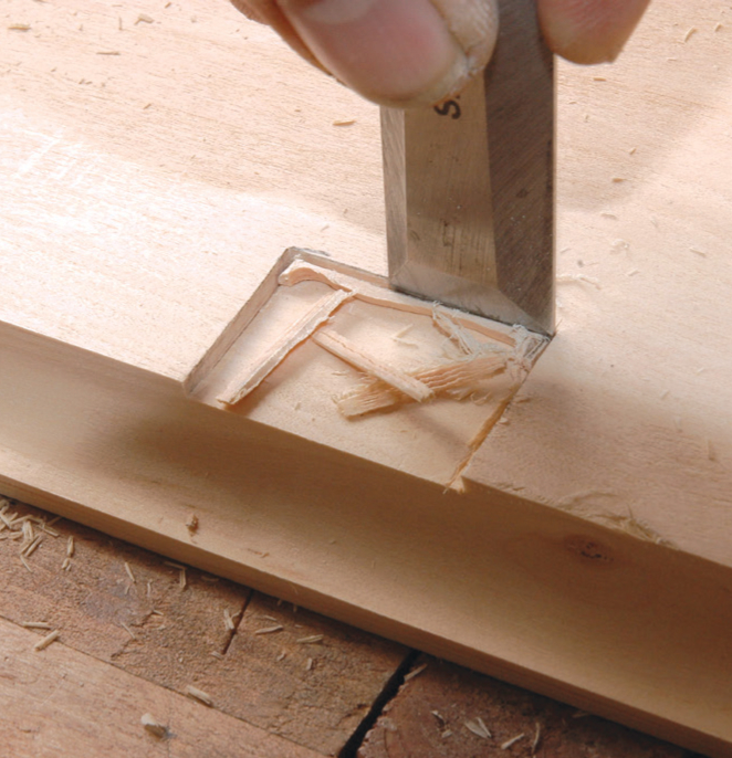 Carving wood with a chisel.