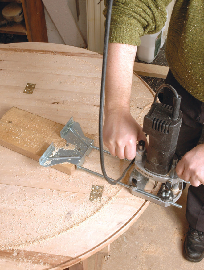 Person using router on wooden table.