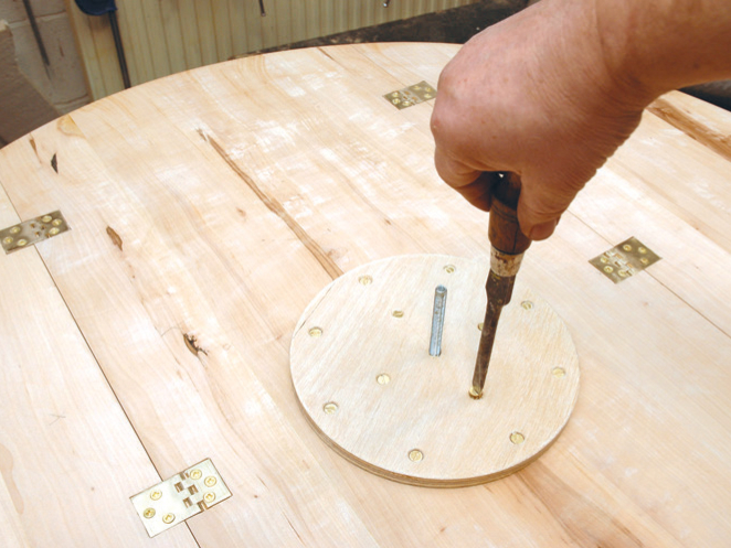 Hand assembling wooden table with screwdriver.