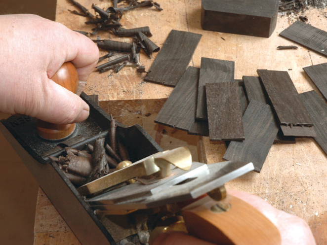 Hand planing wood on a workbench.