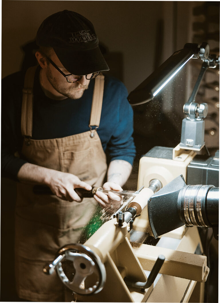 Man carving wood on a lathe machine workshop.