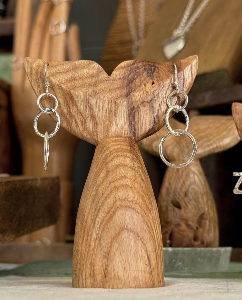 Silver hoop earrings displayed on wooden stand.
