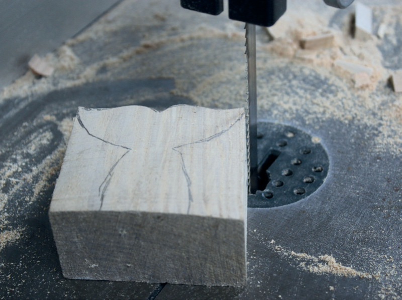 Wood block on bandsaw with markings for cutting.