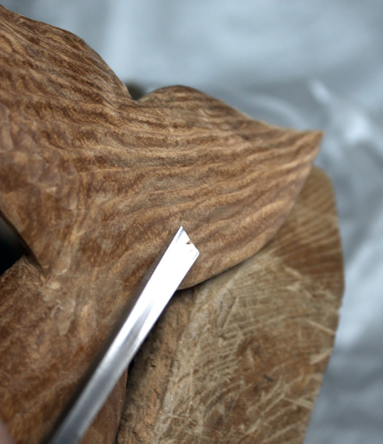 Wood carving with chisel on a textured surface.
