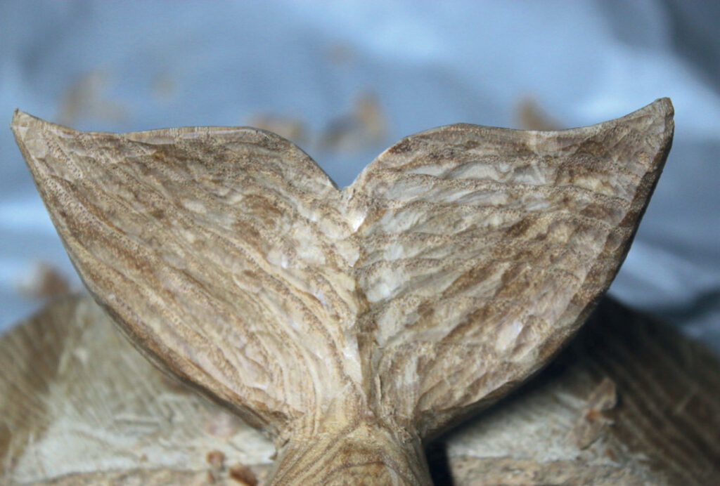 Wooden mermaid tail carving, detailed texture close-up.