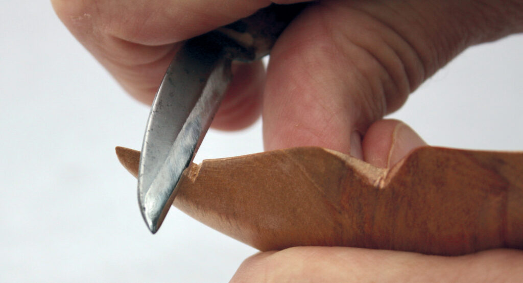 Hand carving wood with sharp knife.