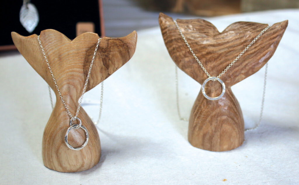 Silver necklaces displayed on wooden stands
