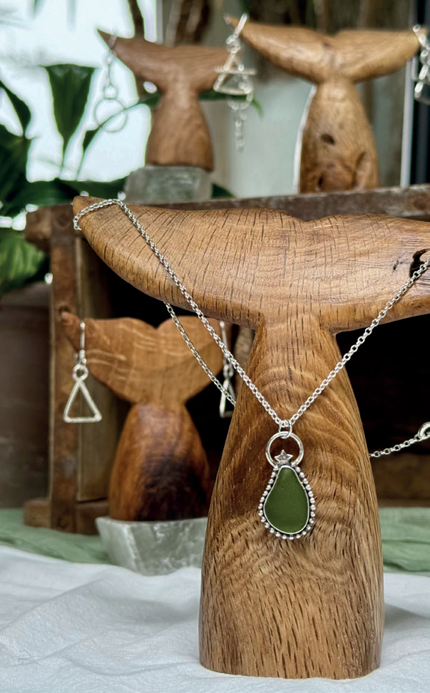 Wooden whale tail with silver pendant display.