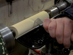Hand using tool on woodworking lathe machine