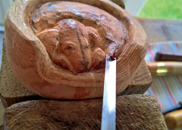 Wood carving in progress with carving tool.