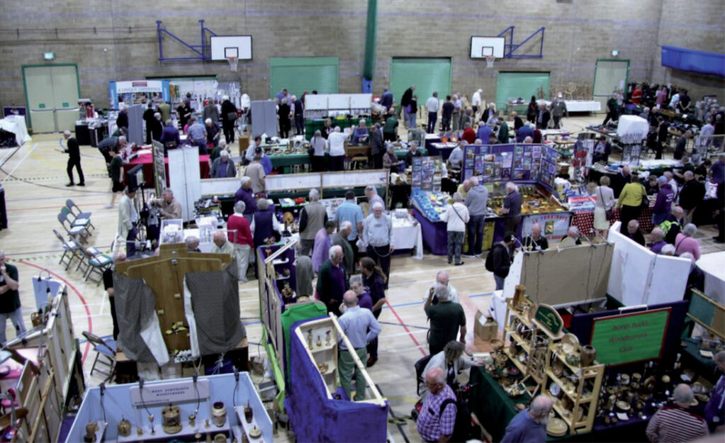 People browsing stalls at indoor exhibition event.