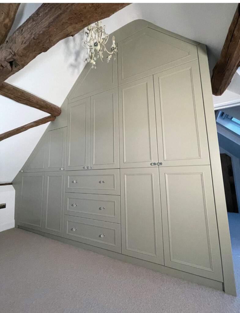 Built-in wardrobe with chandelier in attic room.