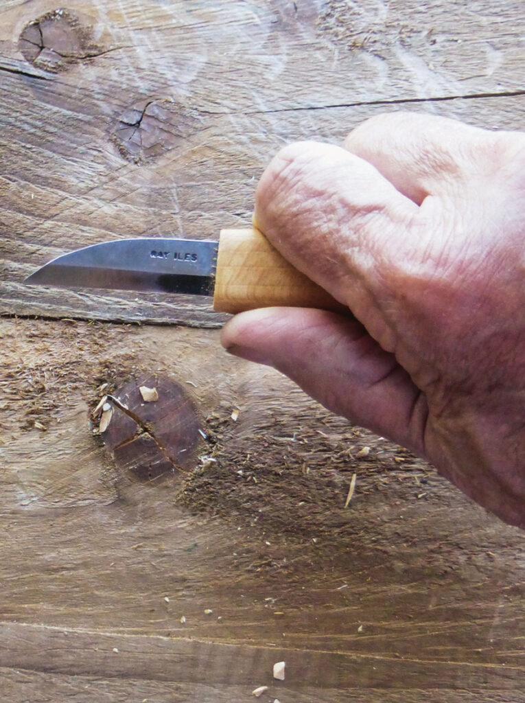 Hand carving wood with a small knife.