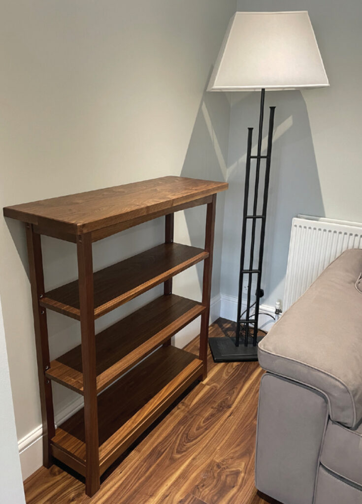 Wooden shelf and lamp in corner of living room.